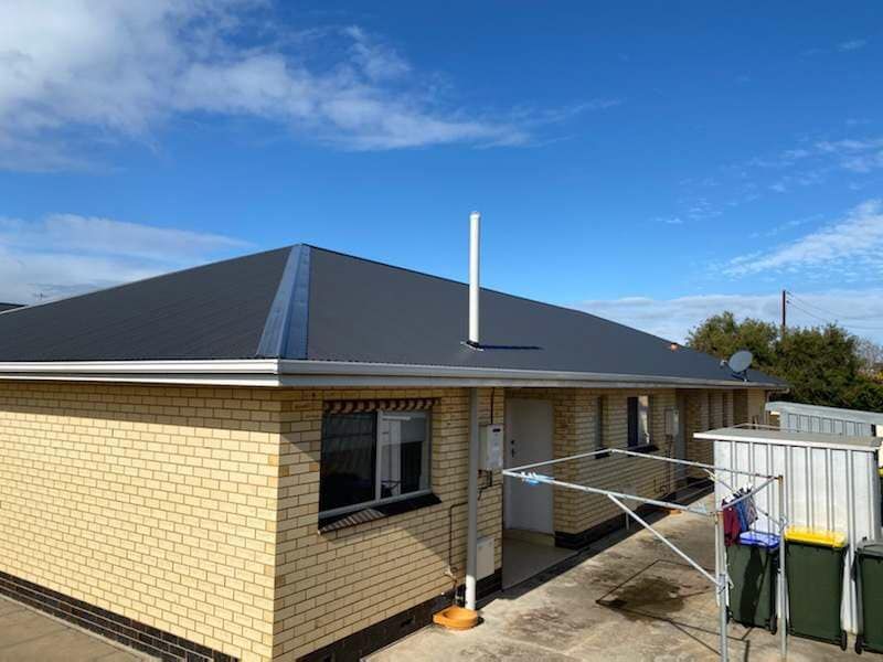 A brick house with a black roof and a blue sky in the background.