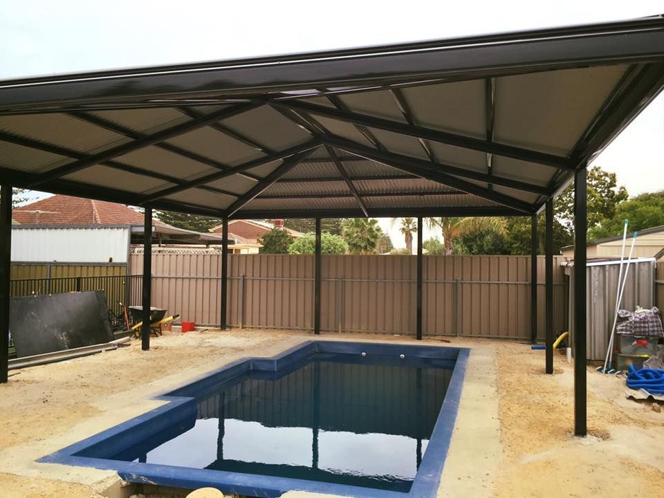 A large swimming pool under a canopy in a backyard