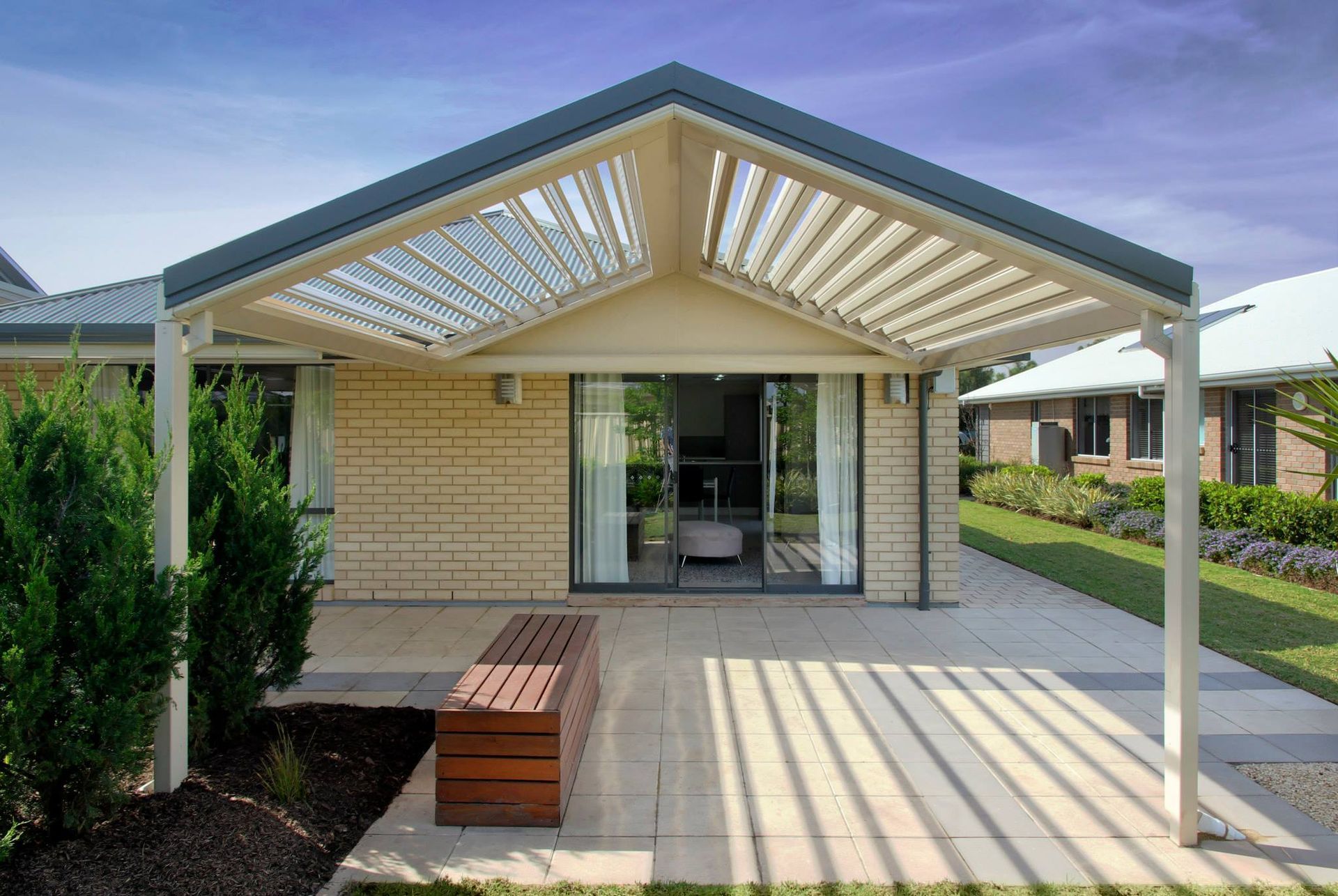 A house with a pergola and a bench in front of it.