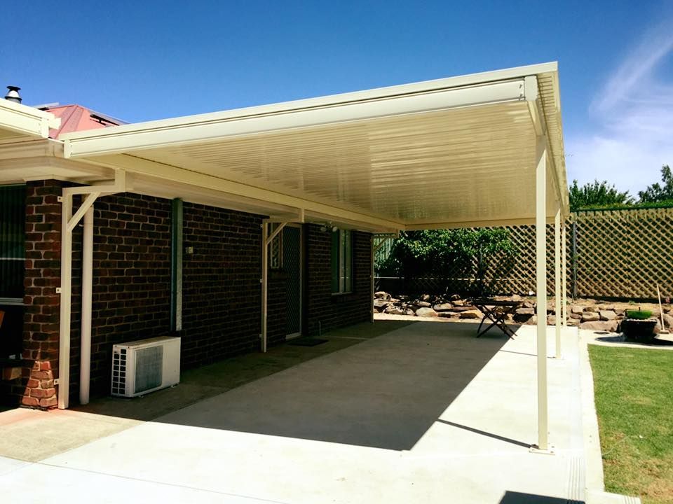 A brick house with a white covered patio in front of it.