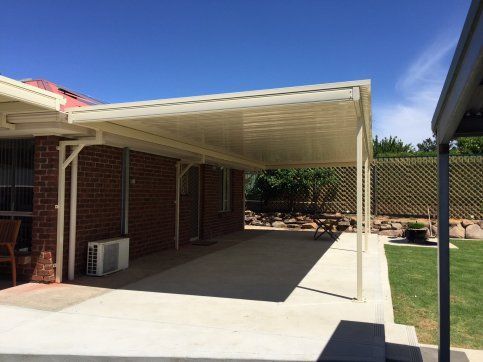There is a carport in the backyard of a brick house.