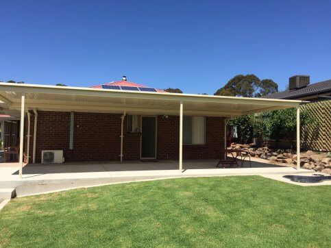 A brick house with a covered patio in the backyard.