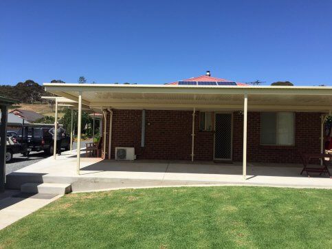 A brick house with a covered porch and a lawn in front of it.