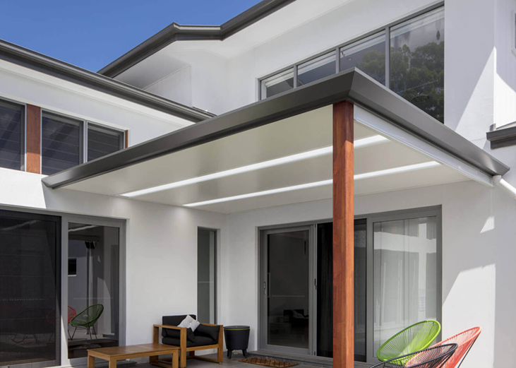 A white house with a covered patio with chairs and a table.