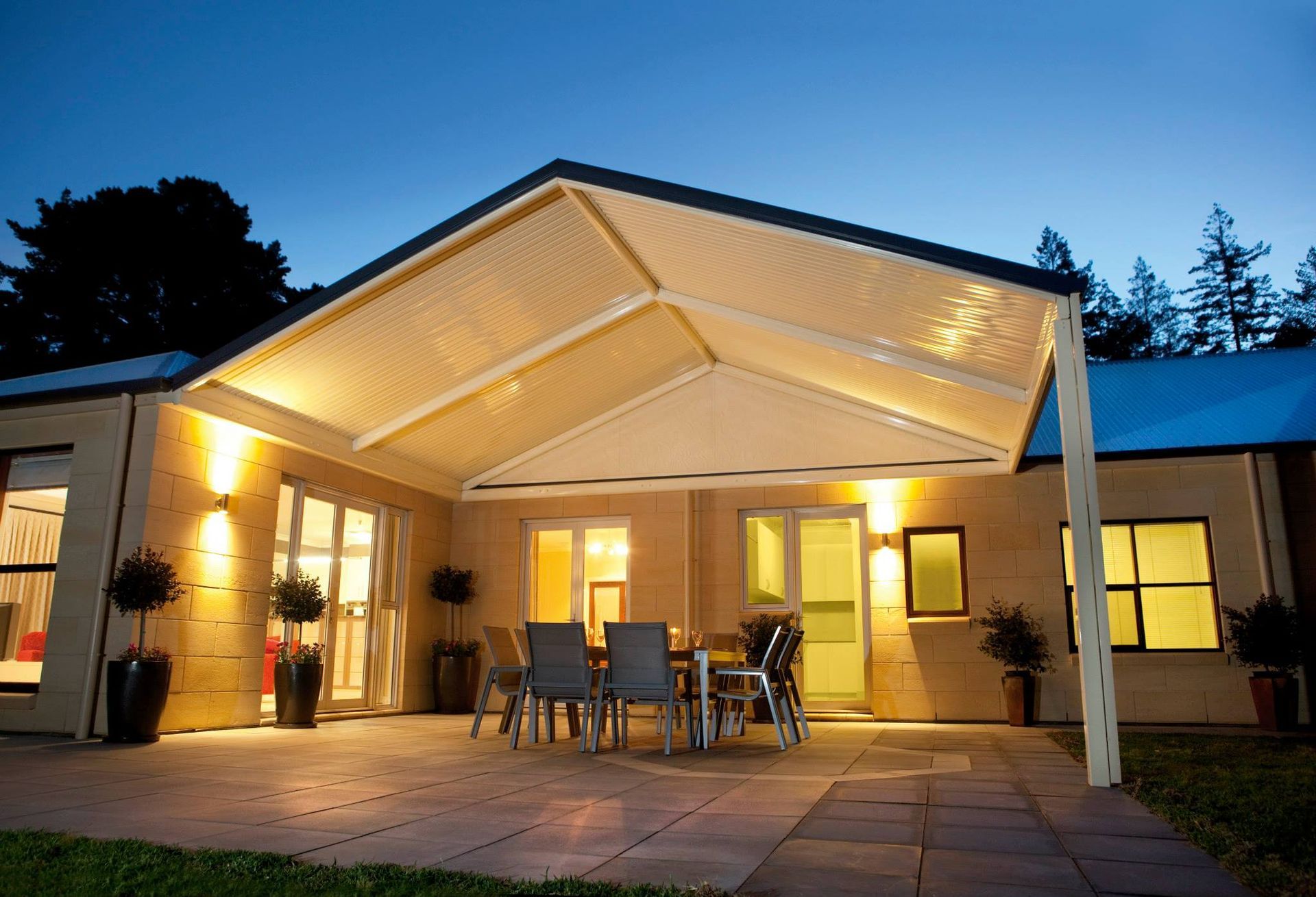 A patio with a table and chairs under a canopy at night