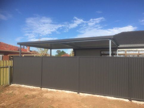 A house with a carport and a fence in front of it.