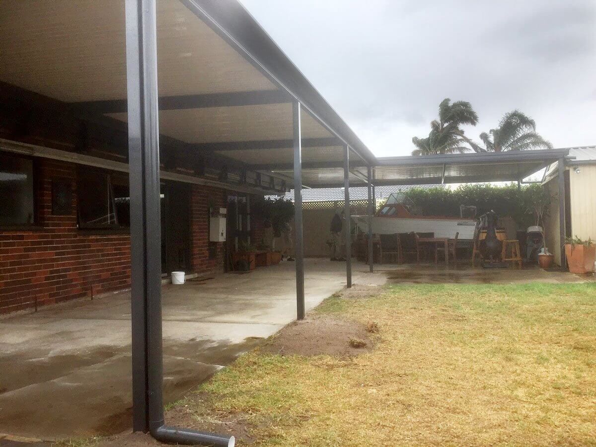 There is a covered patio in the backyard of a house.