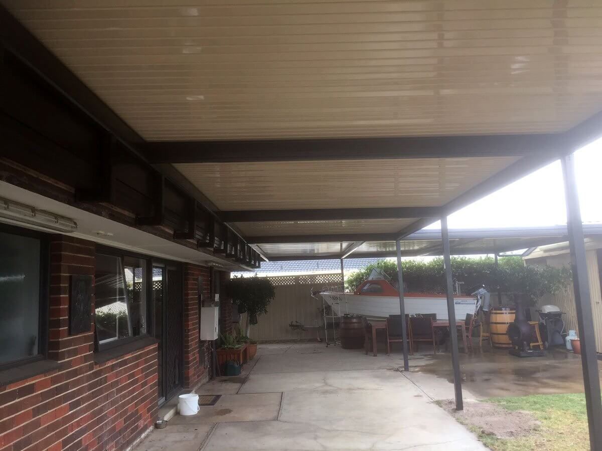 A brick house with a covered patio in front of it.