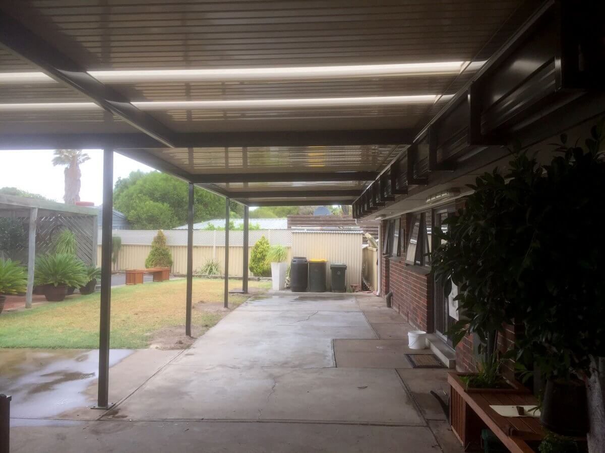 There is a covered walkway leading to the backyard of a house.