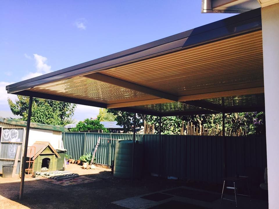 A covered area with a fence and a dog house in the background