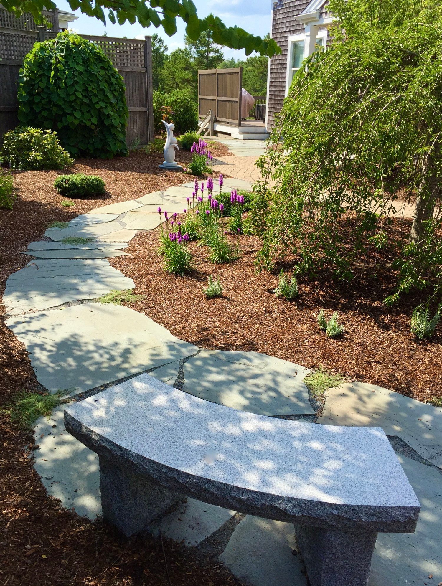 A stone bench sits on the side of a path in a garden.