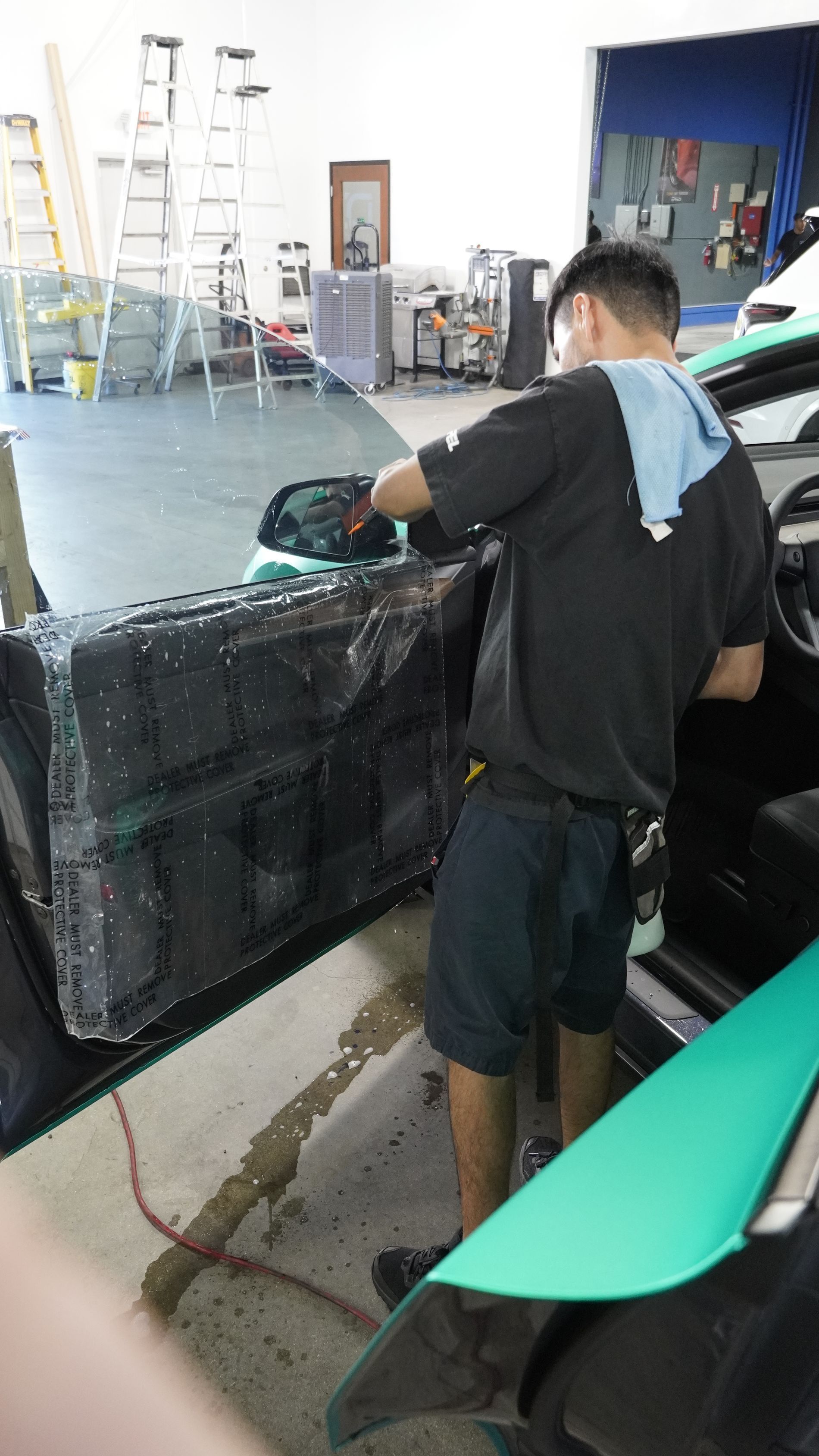 A man is working on a car door in a garage.
