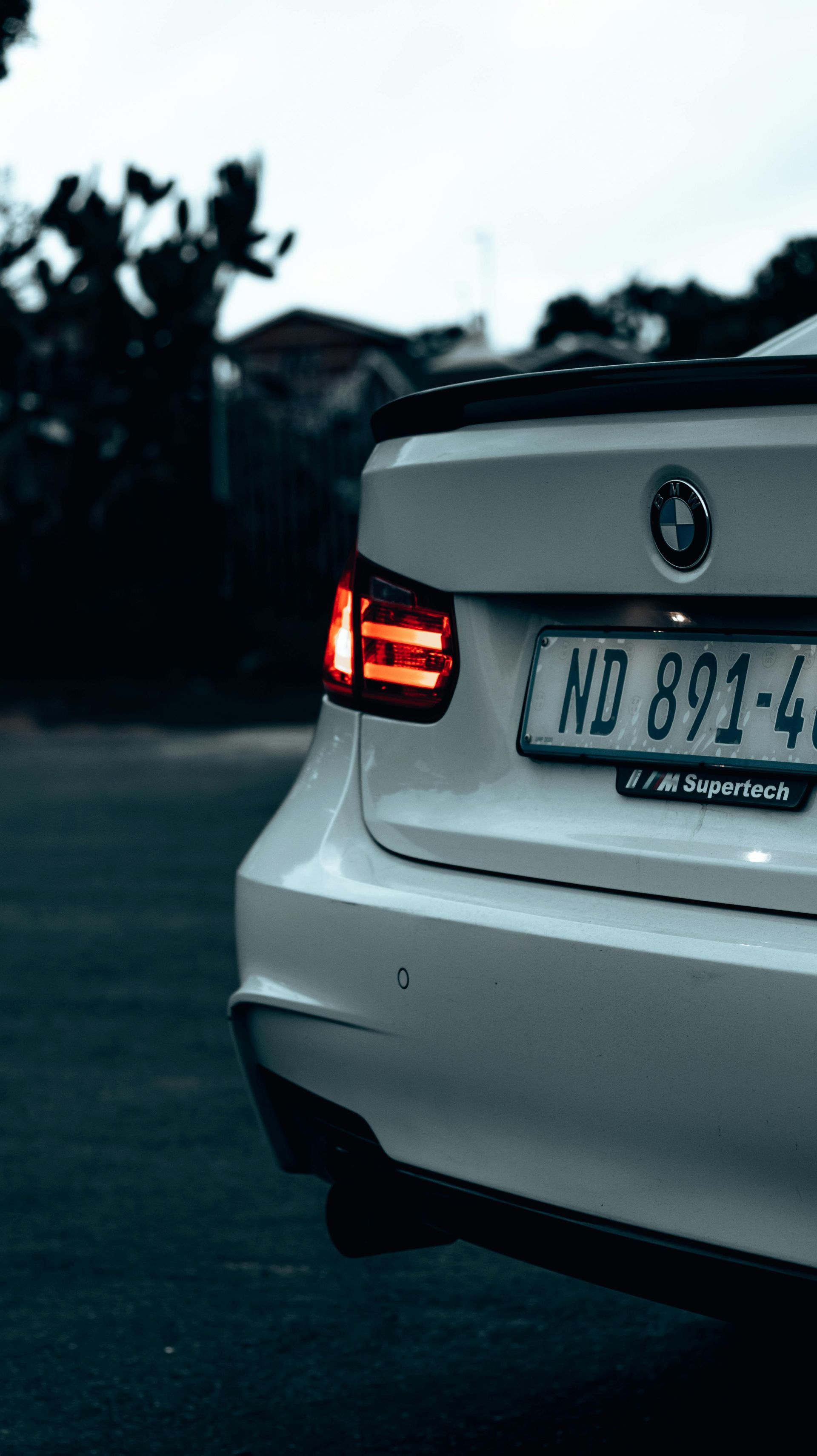 A white bmw is parked on the side of the road.