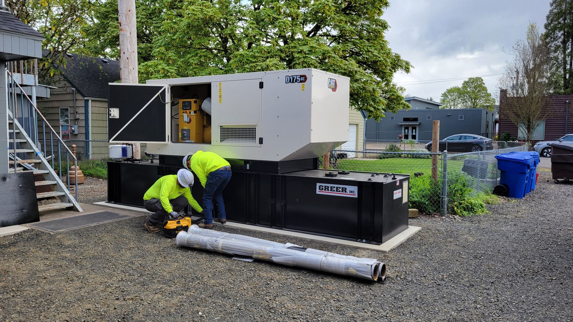 A yellow and gray generator is sitting on the ground in front of a boat.