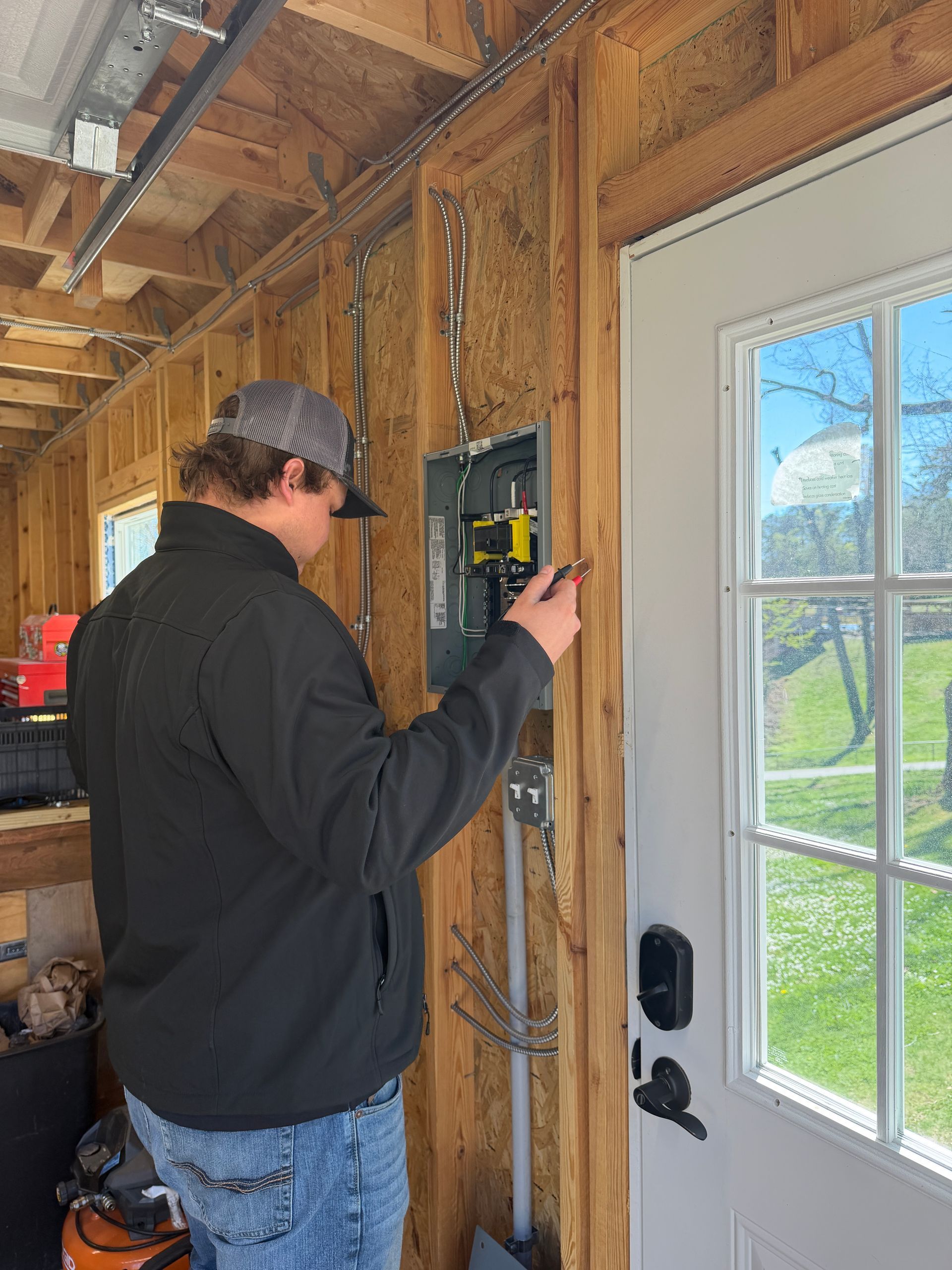 Electrician using a power tool to work on electrical panel.