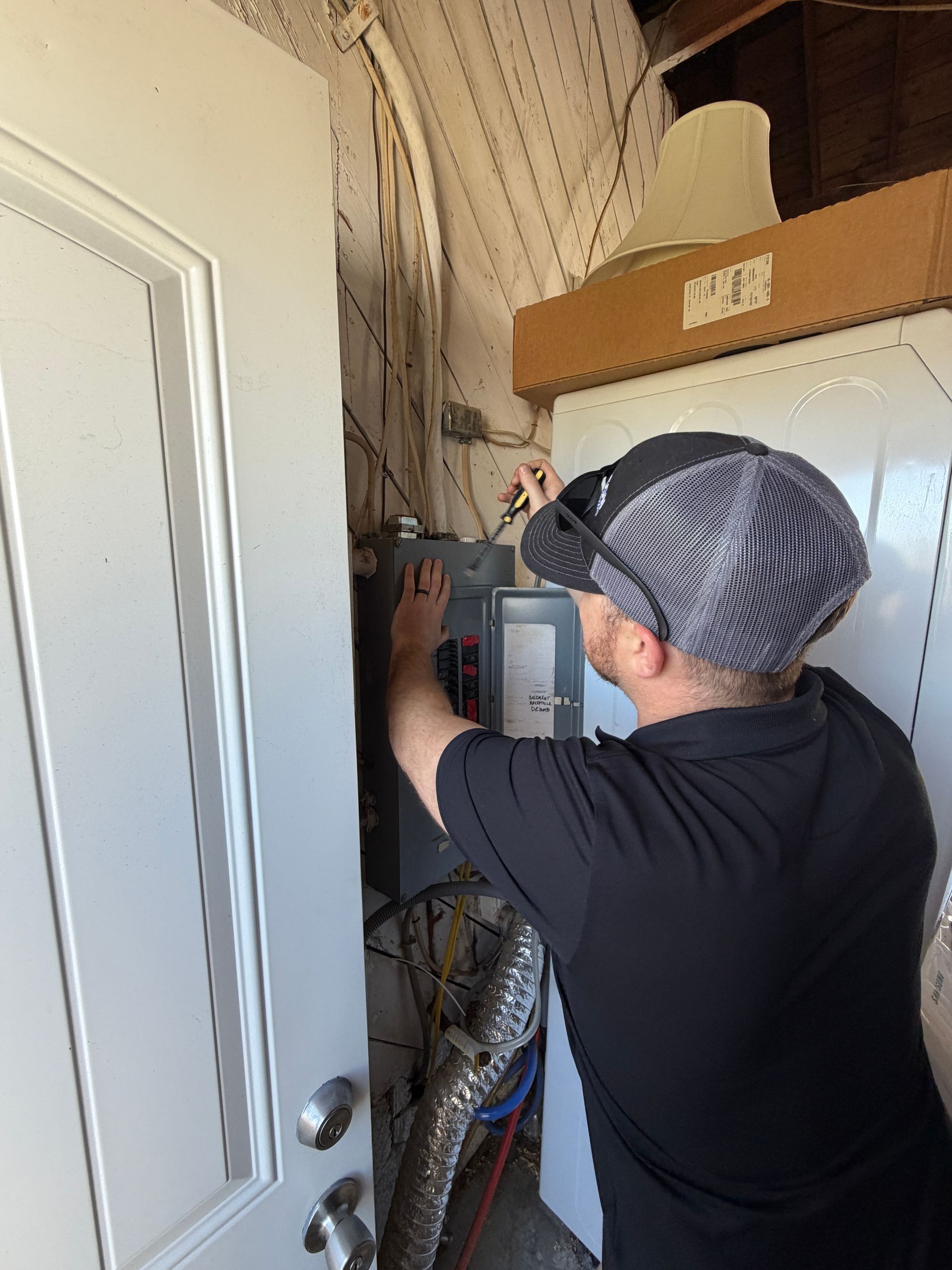 Person using a multimeter to test electrical wiring in a wall.