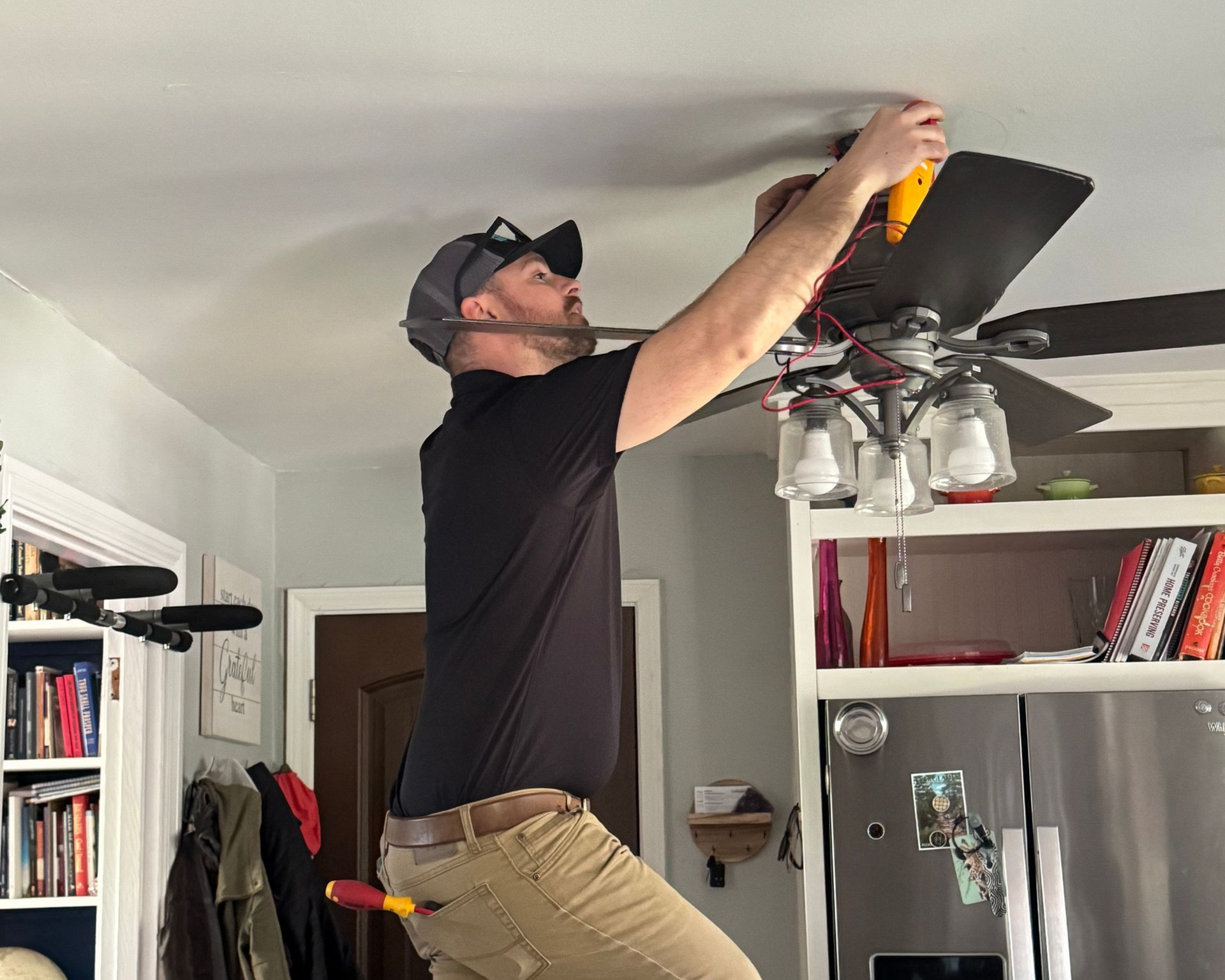 Bedroom with vaulted ceiling, light walls, bed, rug, windows, barn door, and ceiling fan.