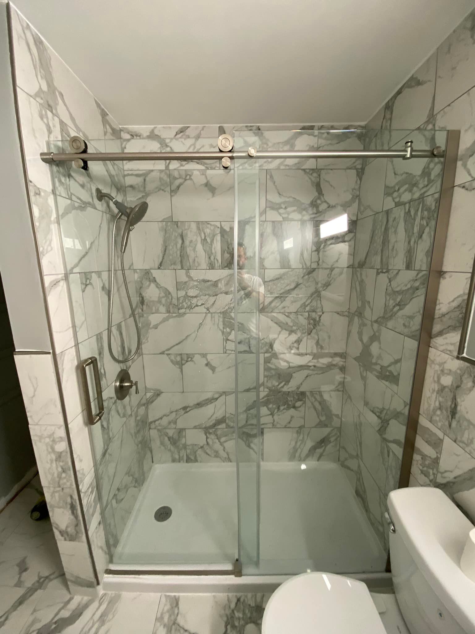 A bathroom with a sliding glass shower door , toilet , sink and mirror.