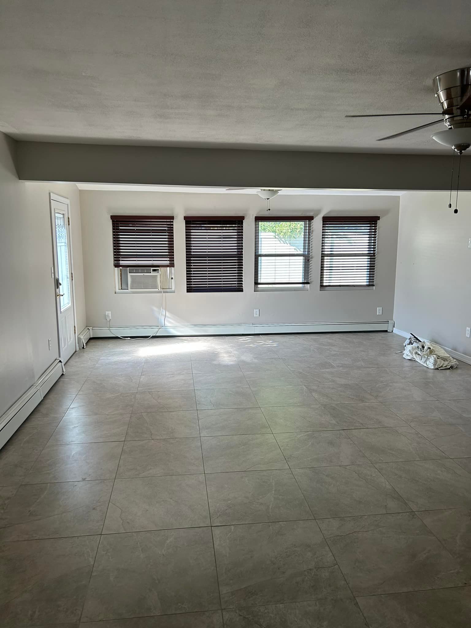 An empty living room with a ceiling fan and a lot of windows.