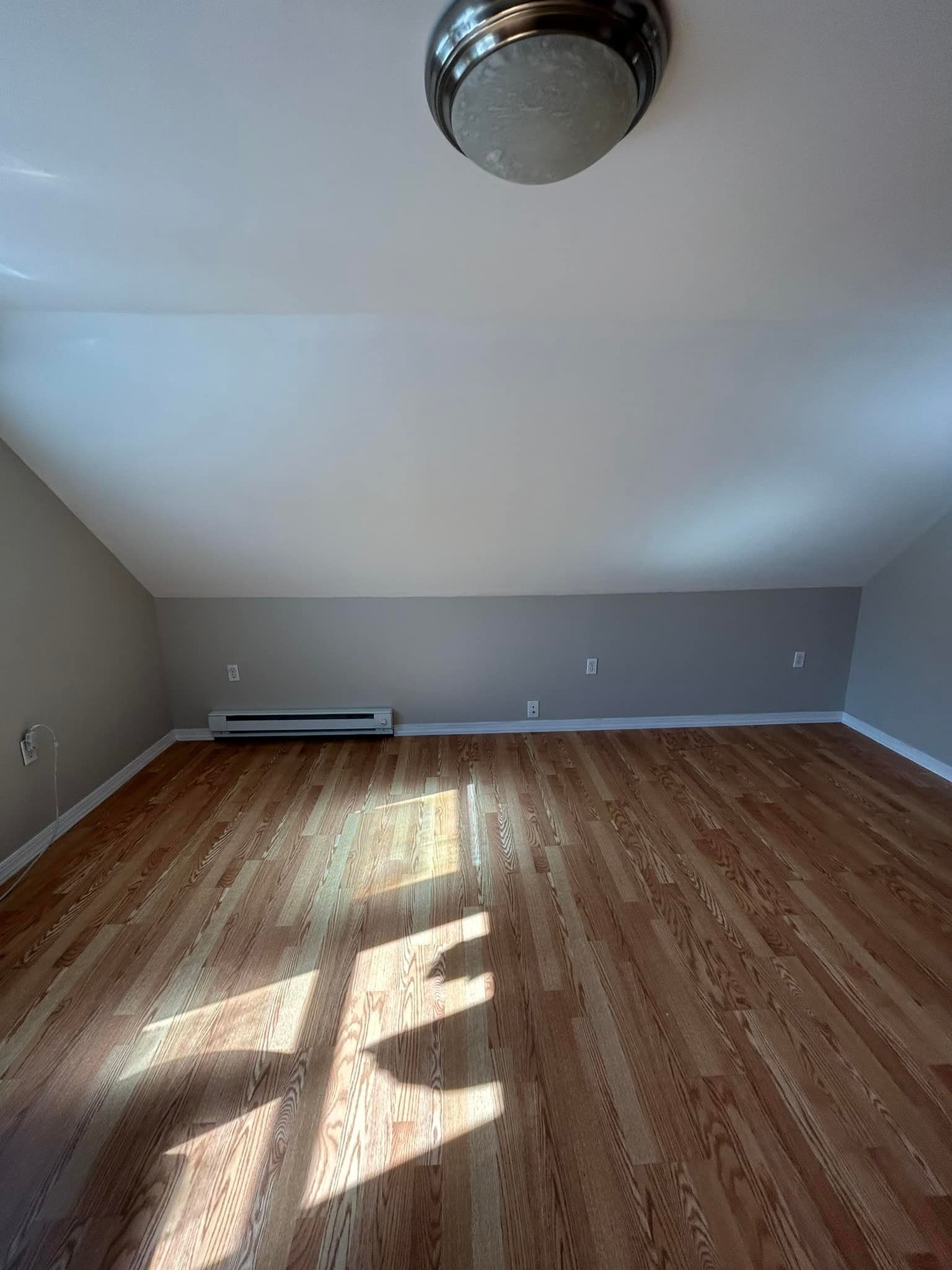 A large empty room with hardwood floors and a ceiling fan.