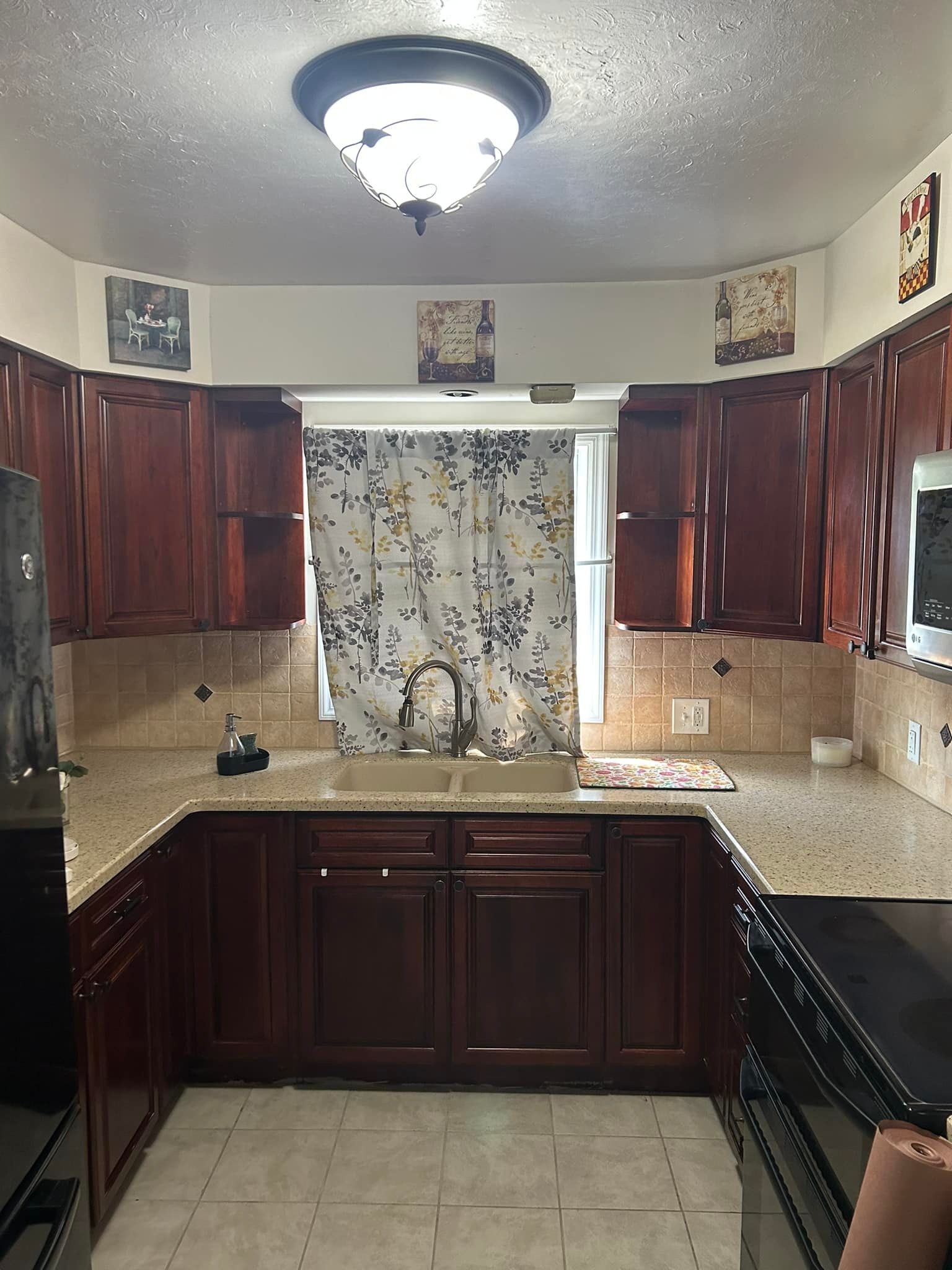A kitchen with wooden cabinets , granite counter tops , a sink , and a window.