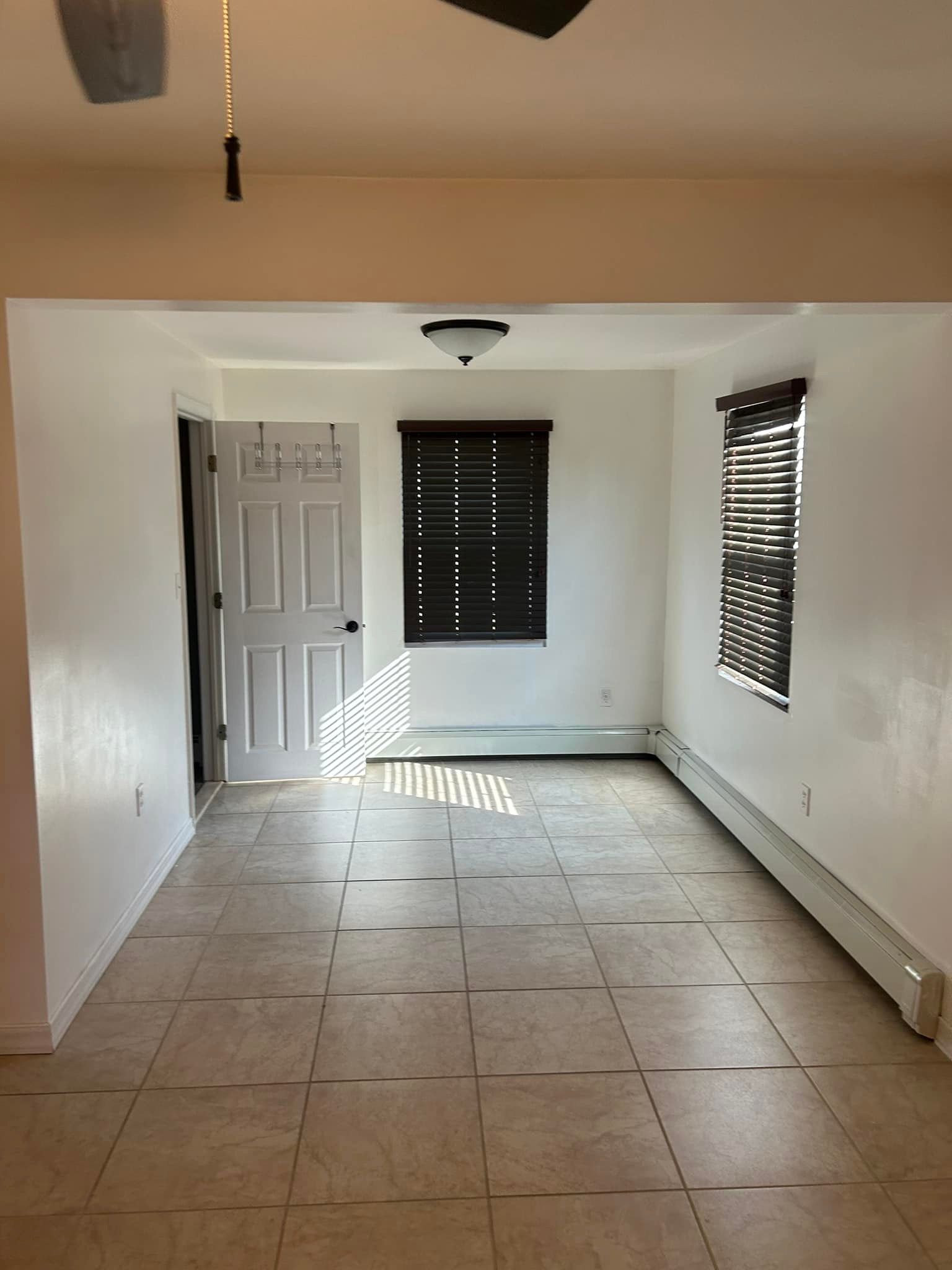An empty living room with tile floors and a ceiling fan