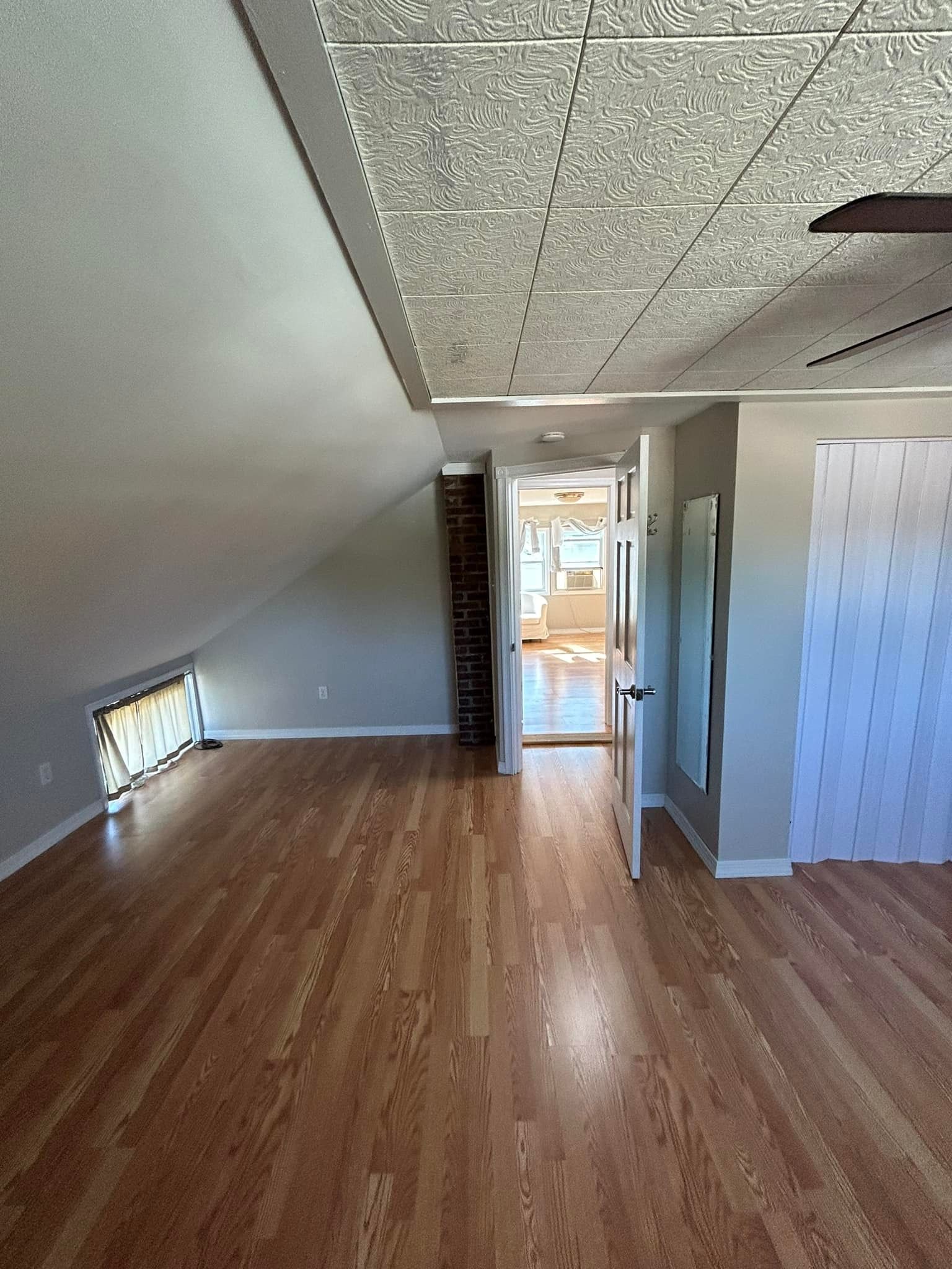 An empty room with hardwood floors and a ceiling fan.