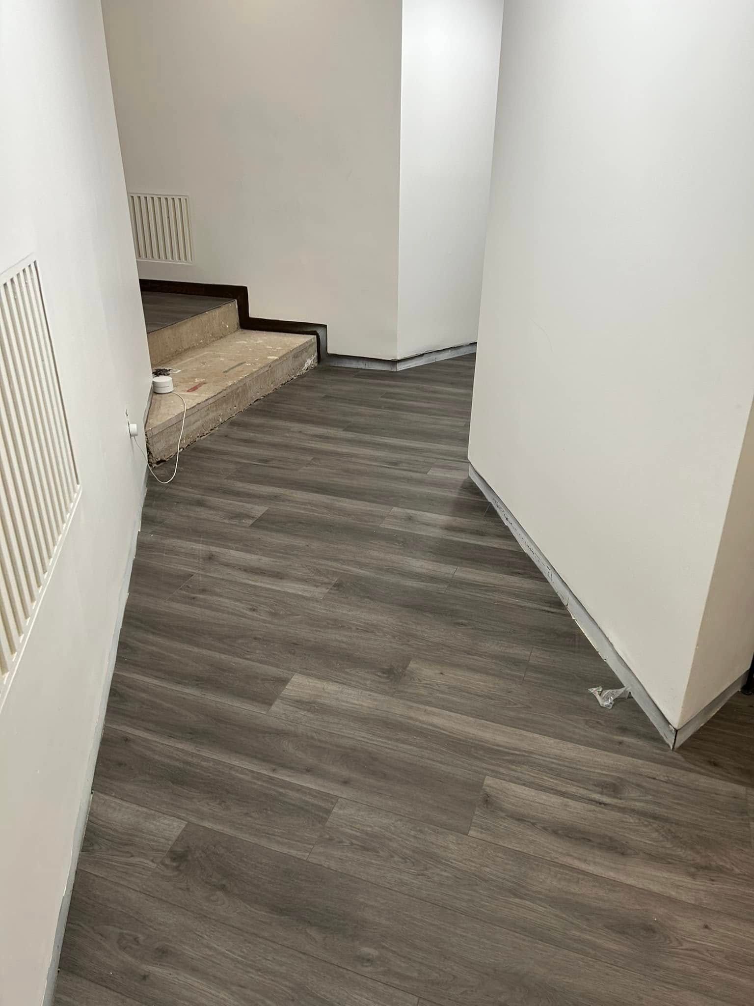A hallway with a wooden floor and stairs.