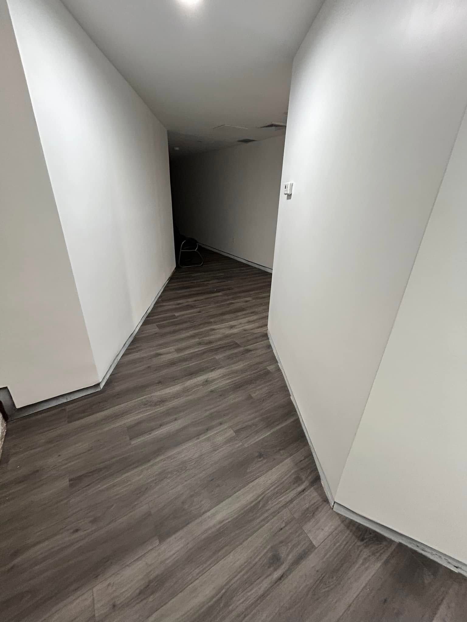 A long hallway with hardwood floors and white walls.