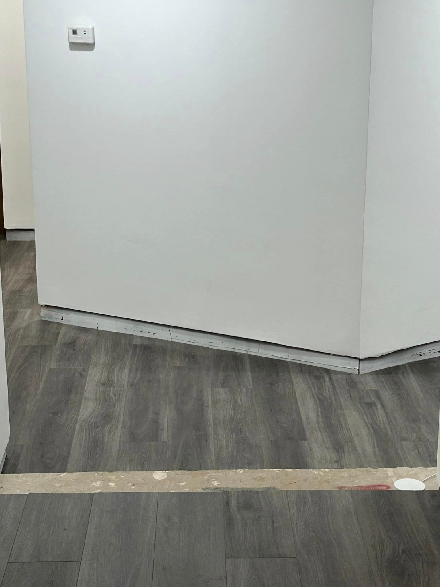 A room with a wooden floor and a white wall.