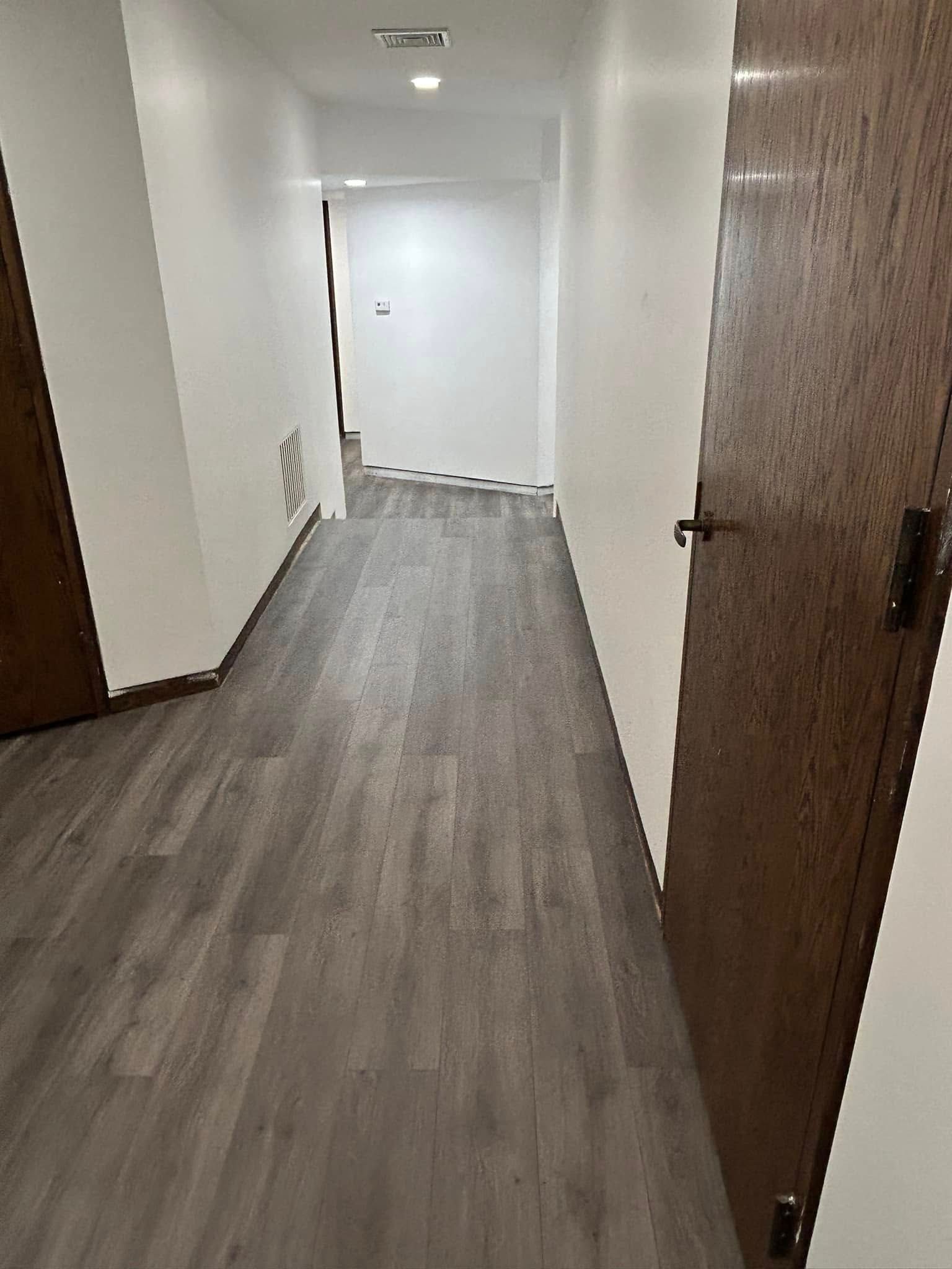 A long hallway with hardwood floors and wooden doors.