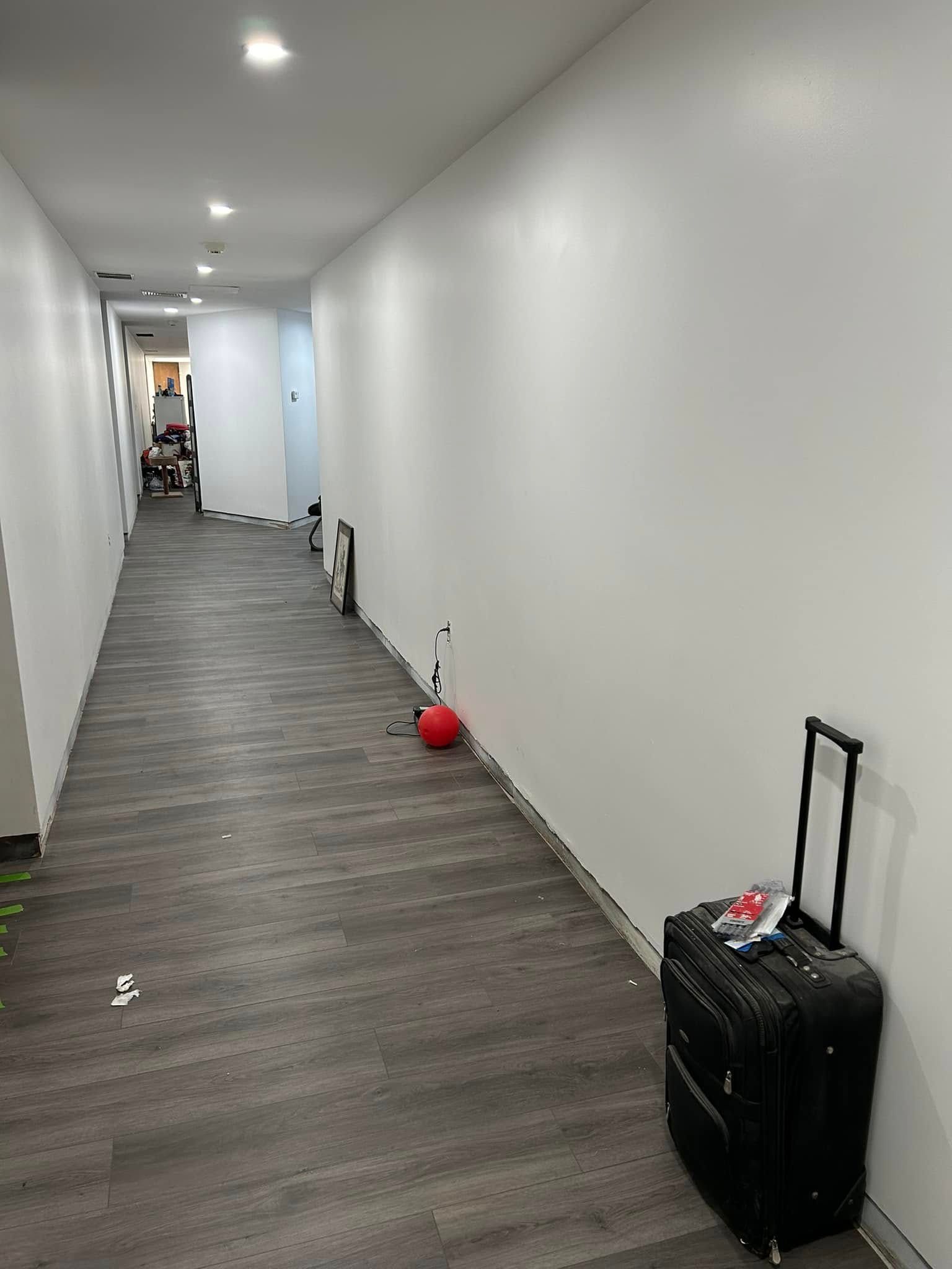 A long hallway with a suitcase and a red ball on the floor.