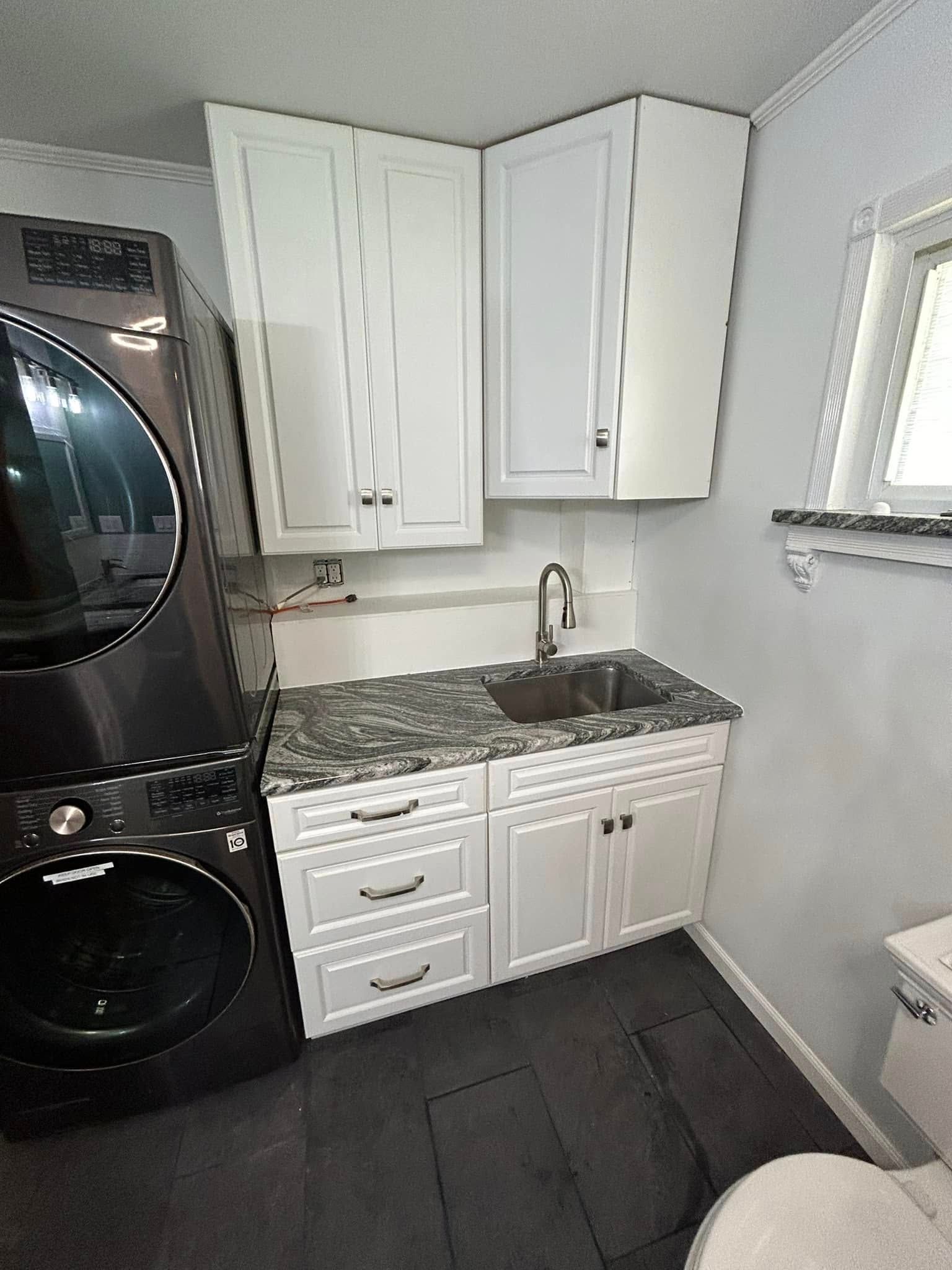 A laundry room with a washer and dryer , sink , cabinets and a toilet.