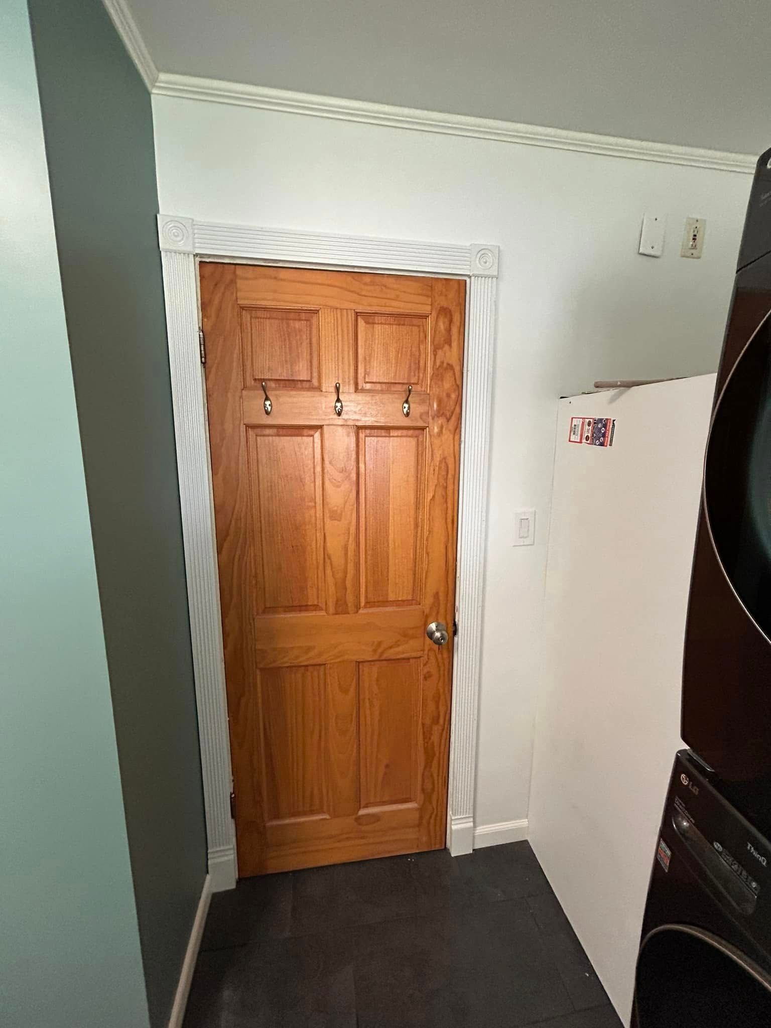 A laundry room with a wooden door and a washer and dryer.
