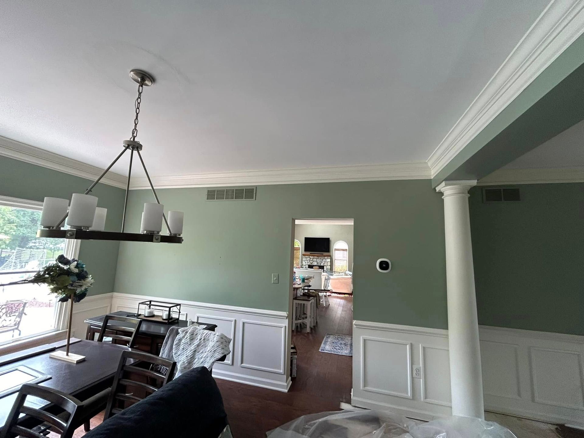A living room with green walls and a chandelier hanging from the ceiling.