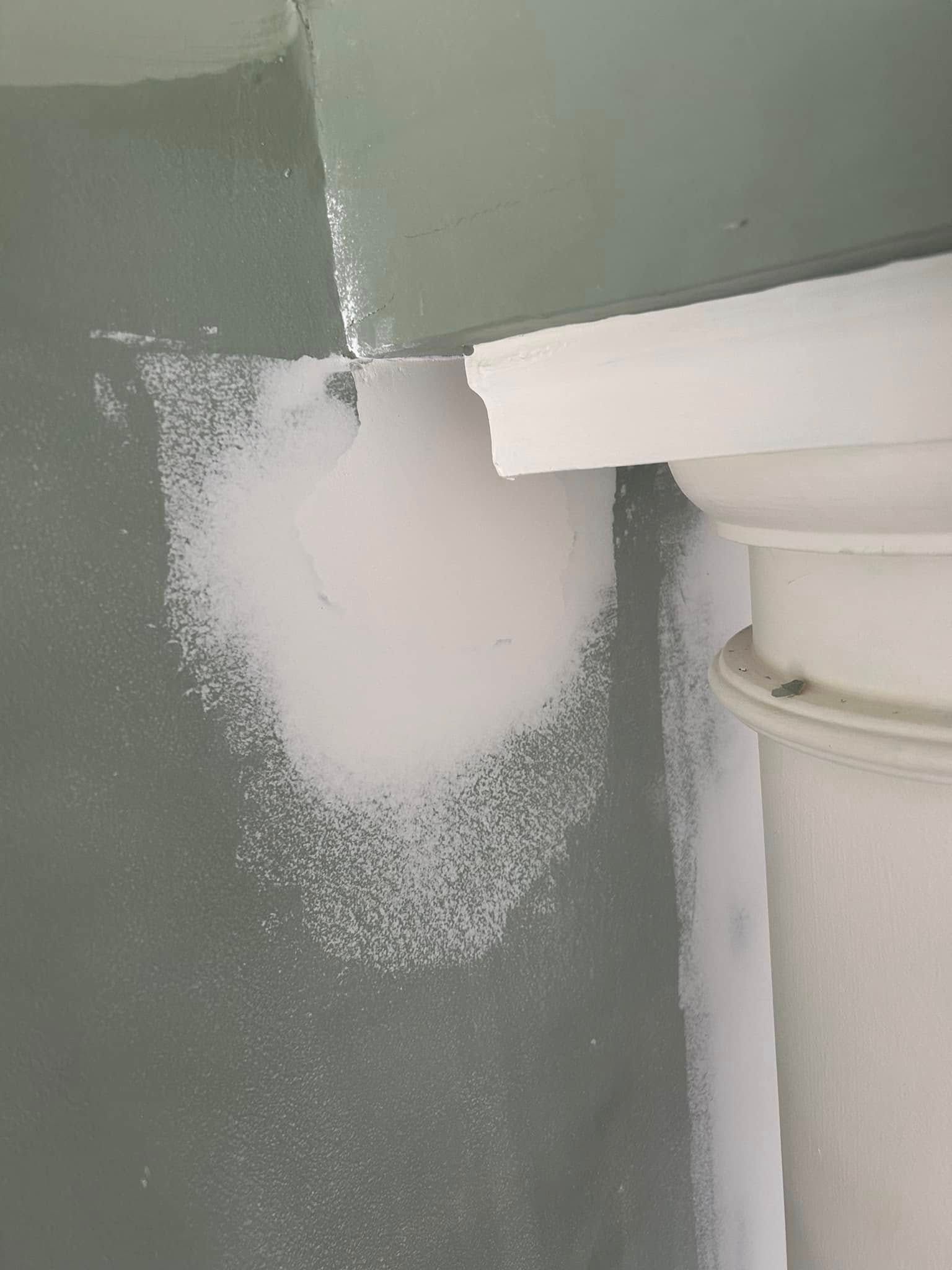 A close up of a toilet in a bathroom with a hole in the wall.
