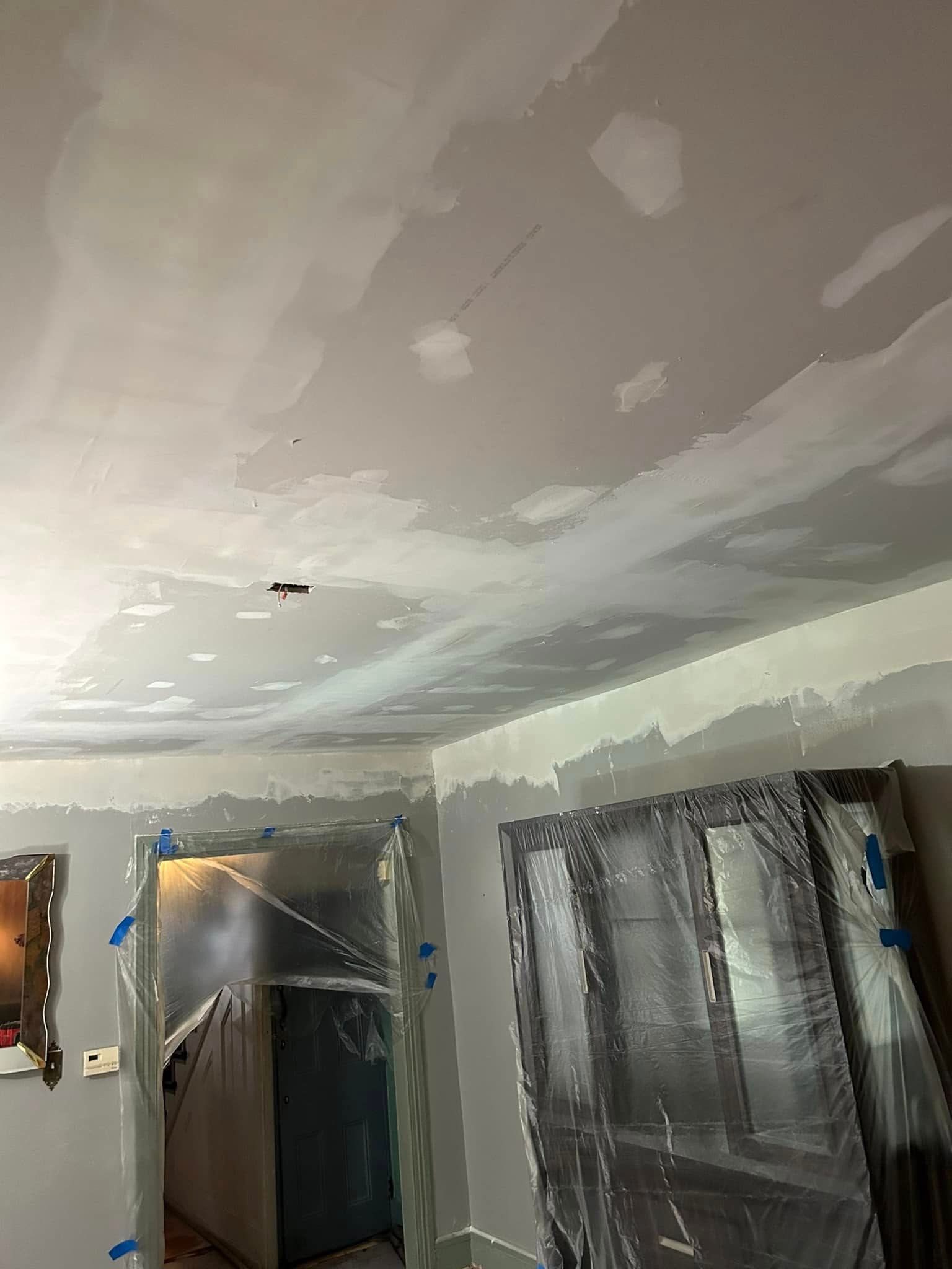A living room with a ceiling that is being painted.