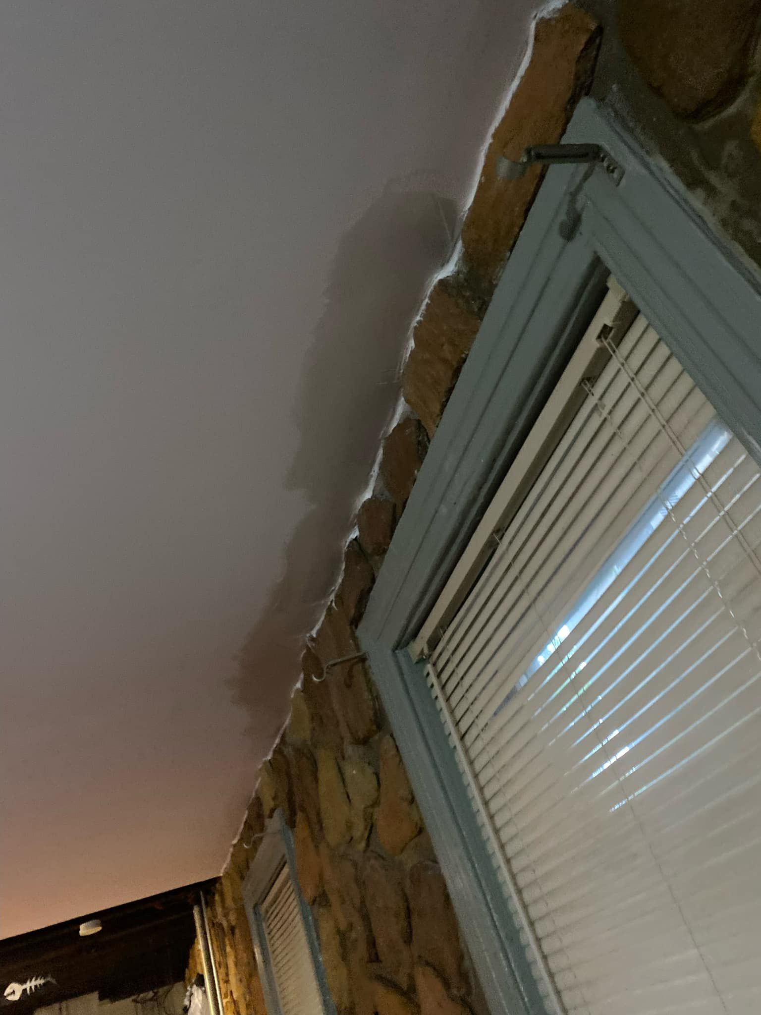 A room with a stone wall and a window with blinds on it.