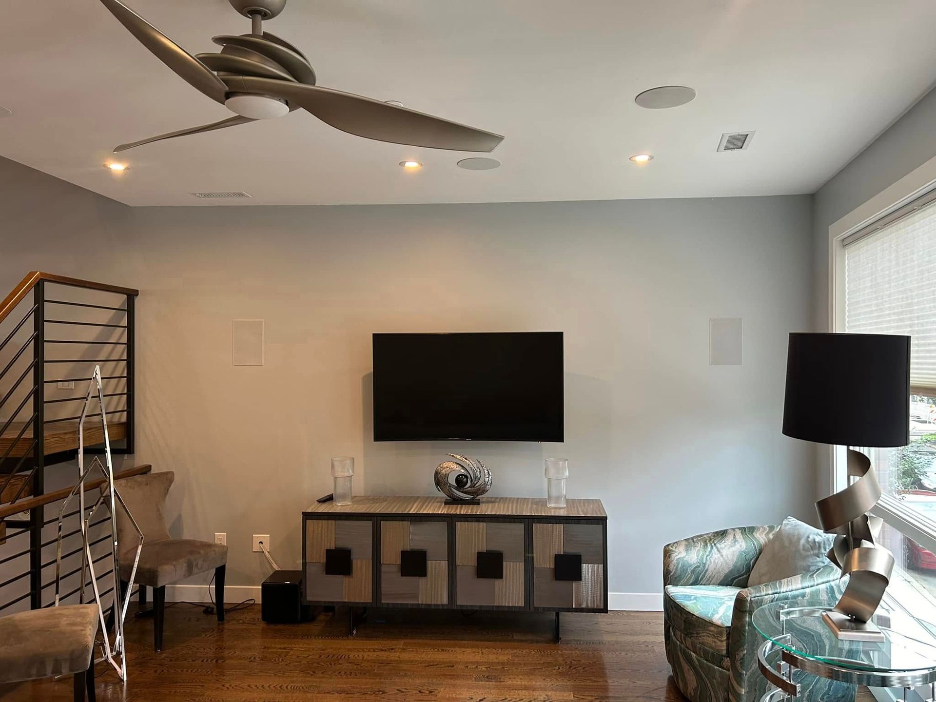 A living room with a ceiling fan and a flat screen tv on the wall.