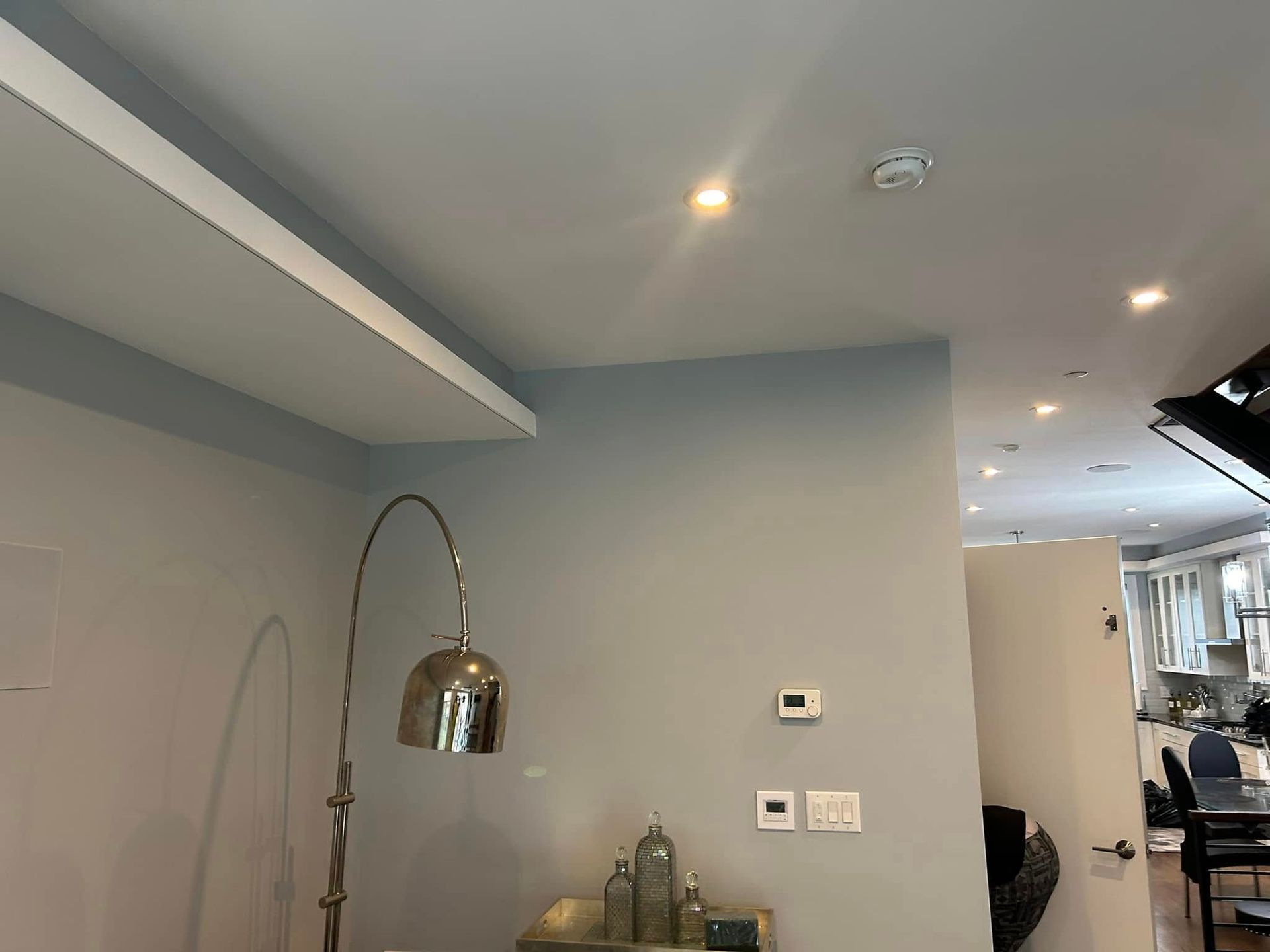 A living room with a lamp and a shelf on the ceiling