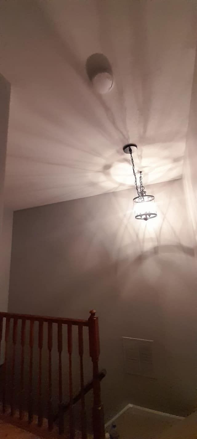 A ceiling fan is hanging from the ceiling of a room next to a staircase.