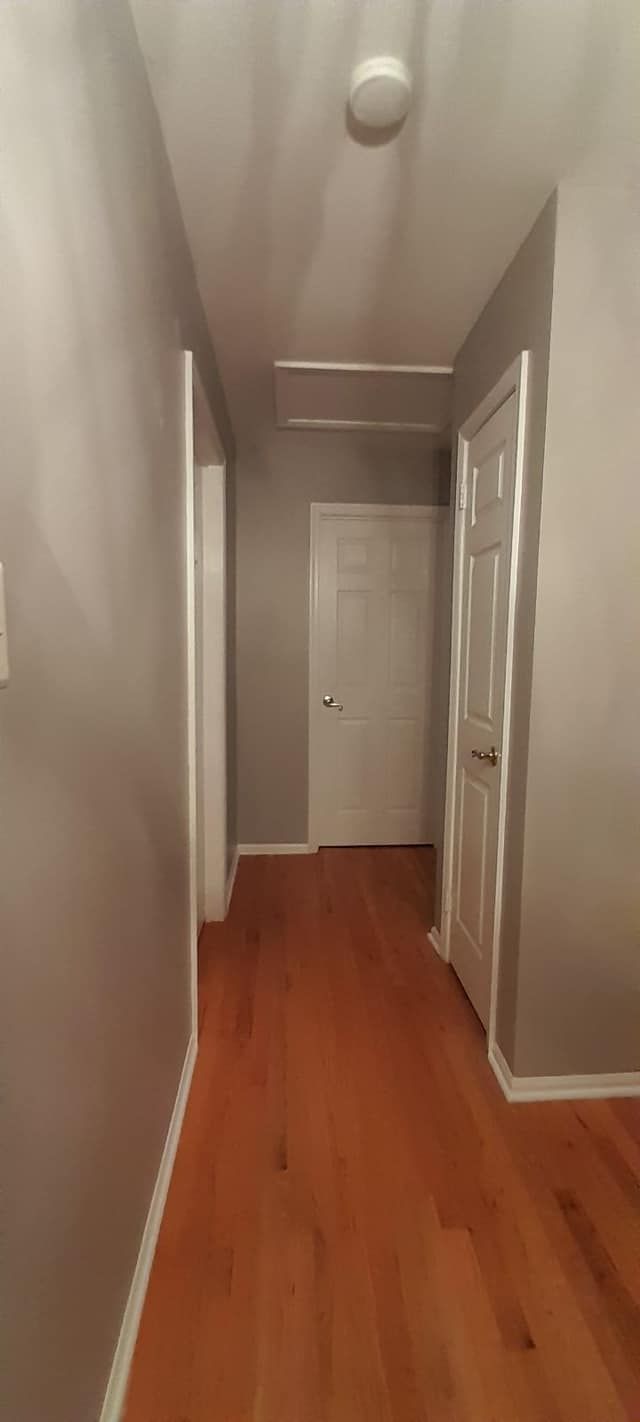 A long hallway with hardwood floors and gray walls.