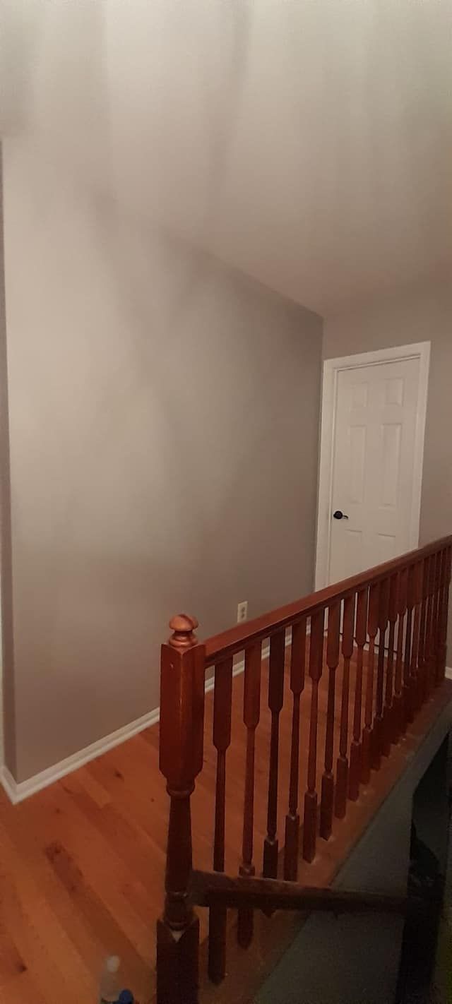 A staircase with a wooden railing and a wooden floor in a room.