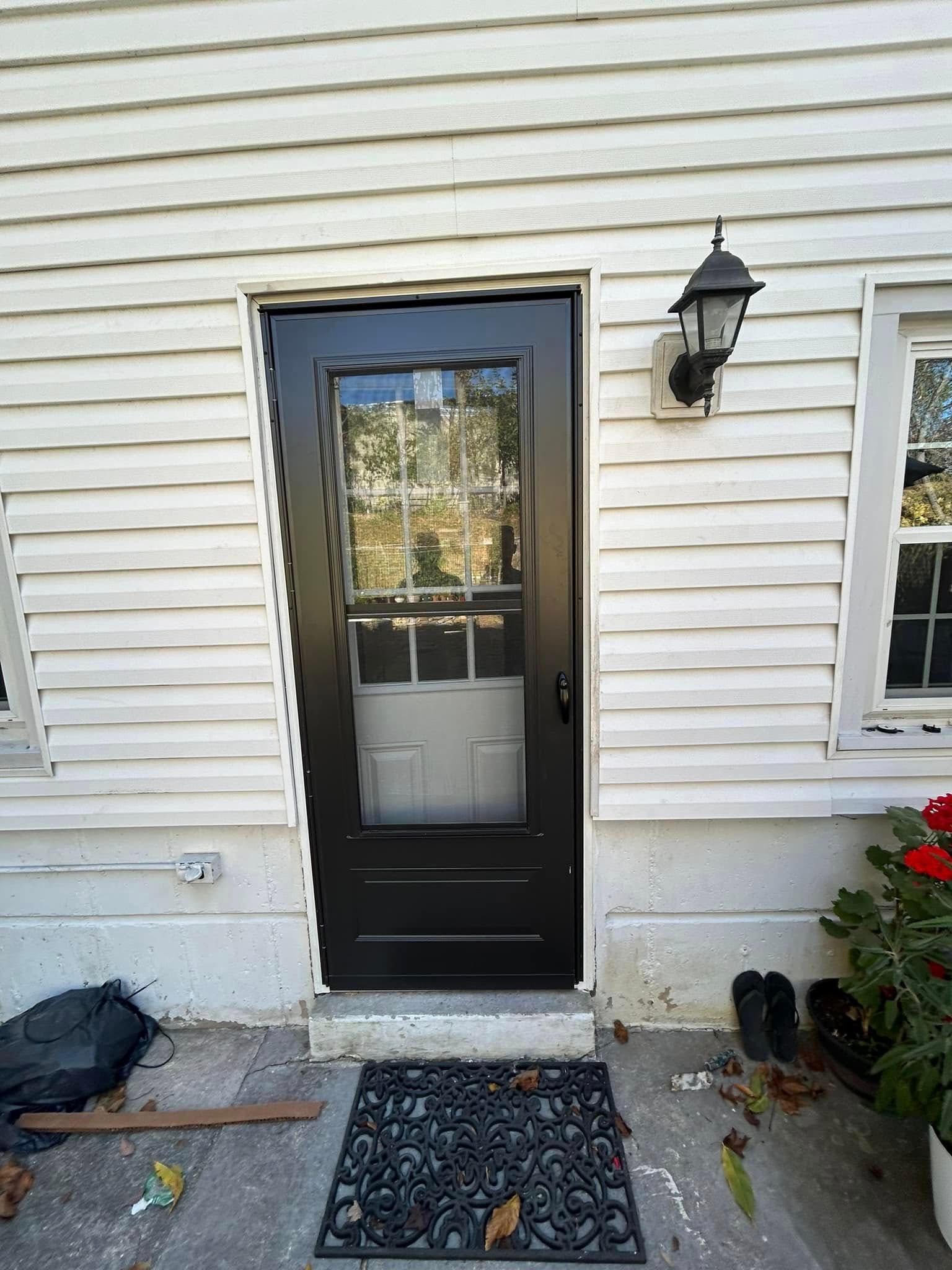 A black door is sitting on the side of a white house.