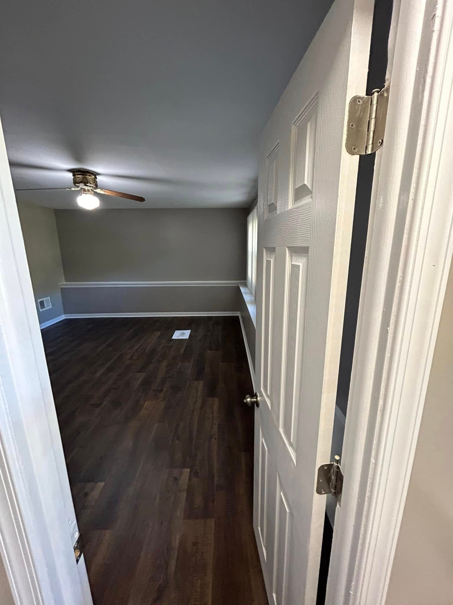 A doorway leading to a living room with hardwood floors and a ceiling fan.