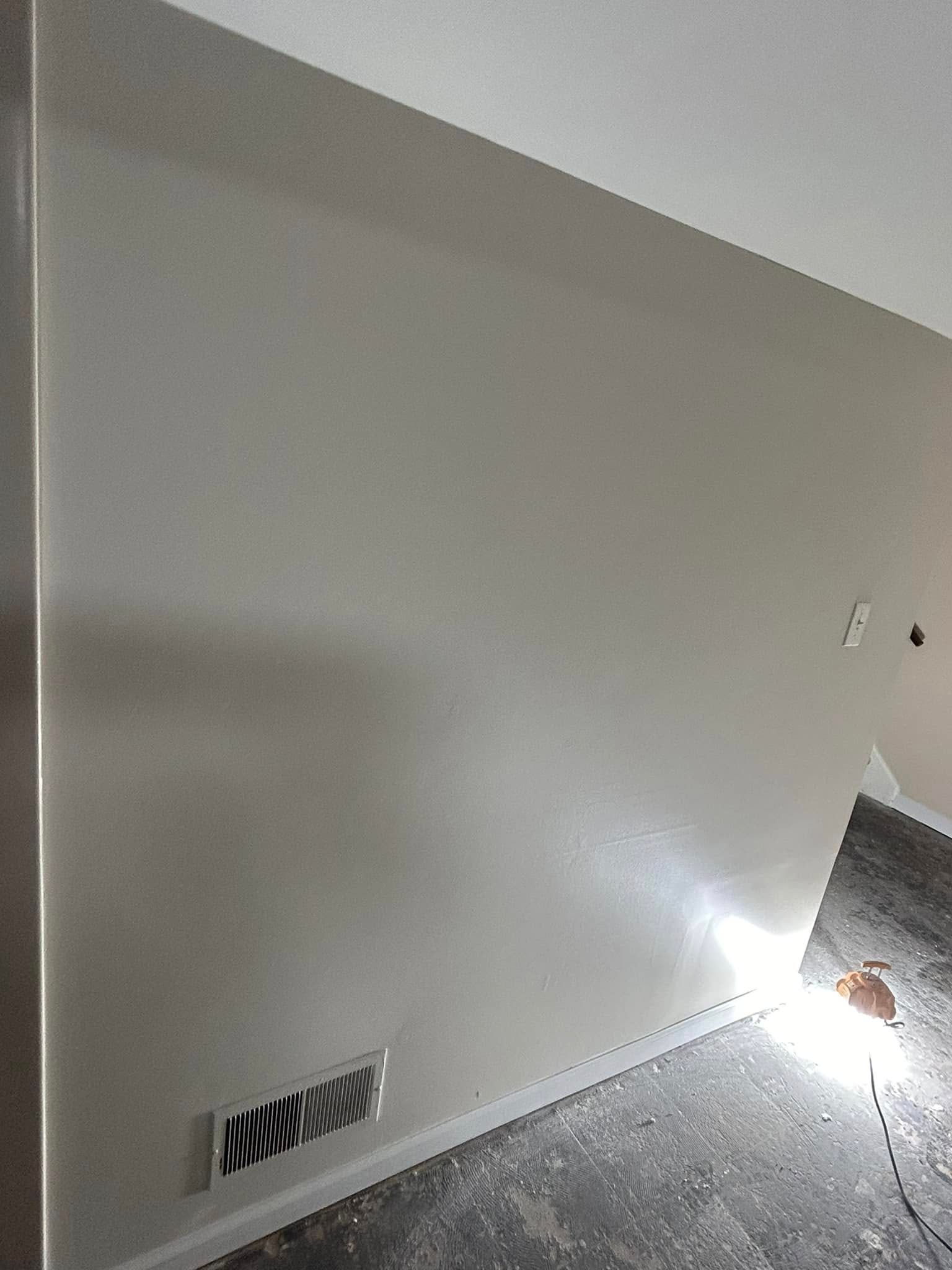 A room with a white wall and a vent on the wall.