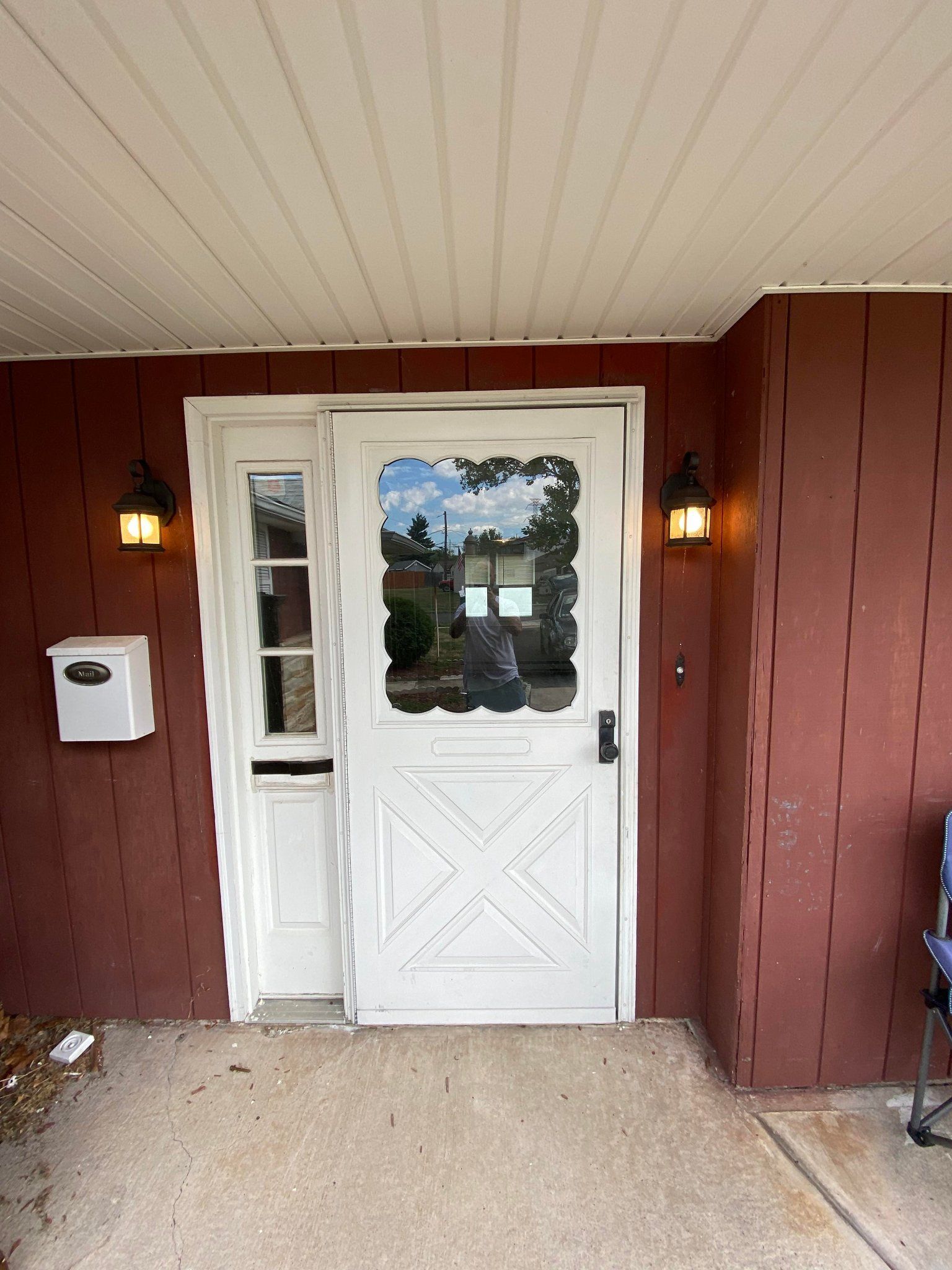 A white door with a glass window is on a red house.