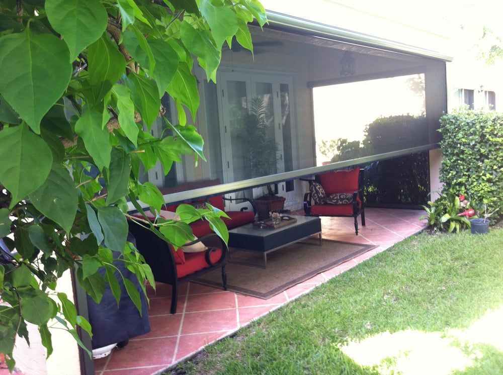 A screened in porch with a couch , chairs , and a coffee table.