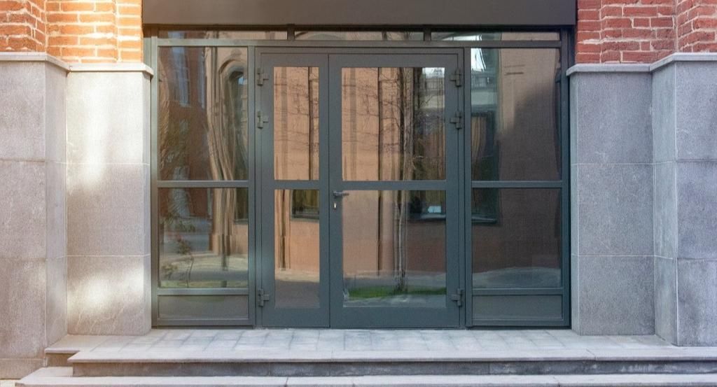 A brick building with a glass door and stairs leading to it.