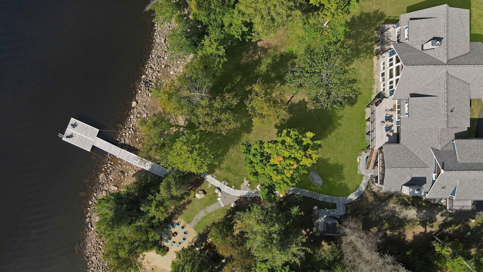 An aerial view of a lake surrounded by trees and a road.